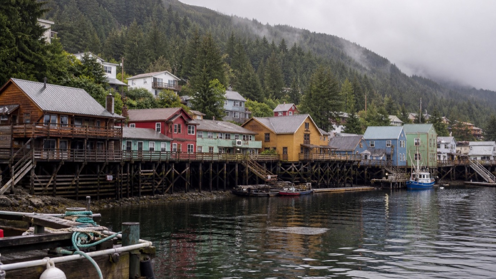 Ketchikan waterfront buildings on pilings below misty forested hills