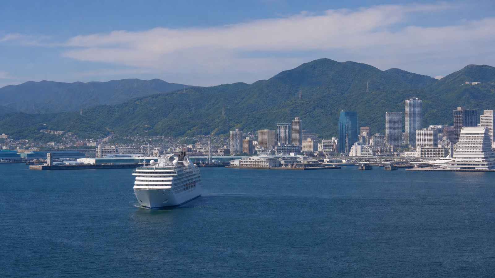 Unbranded cruise ship approaching a Japanese port with mountains and a realistically scaled waterfront city