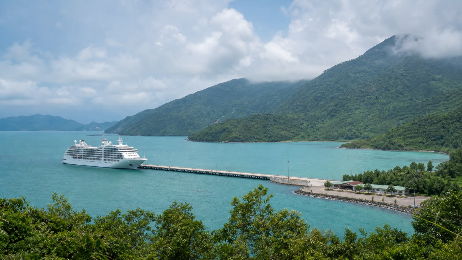 Chan May cruise port with an unbranded ship, green mountains and a low coastal terminal