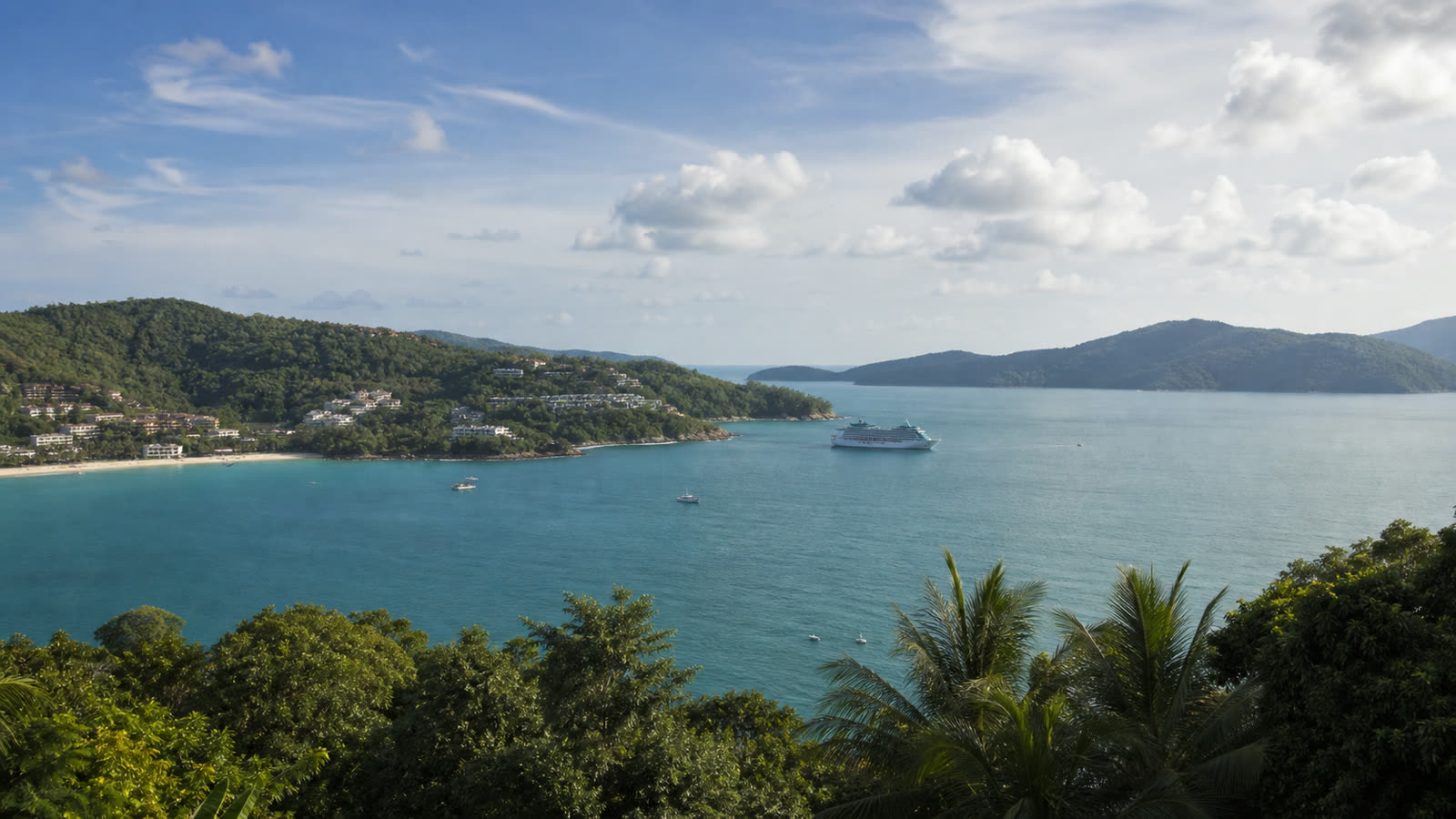 Unbranded cruise ship off Phuket with tender boats, tropical water and a developed shoreline