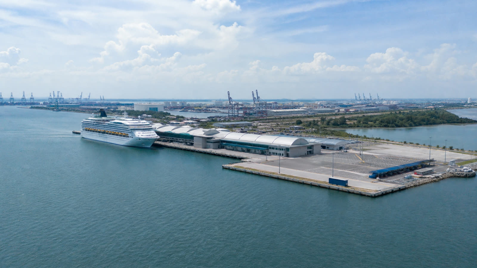 Port Klang cruise terminal with an unbranded ship and working harbor infrastructure