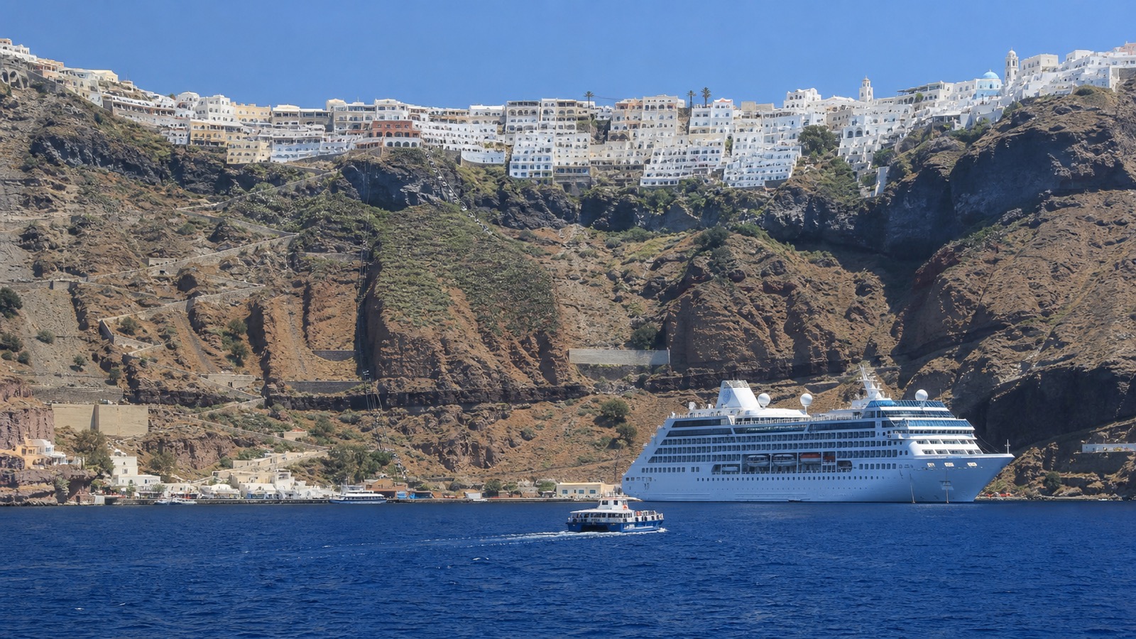 Santorini caldera with an unbranded cruise ship, tender boat and Fira above the cliffs