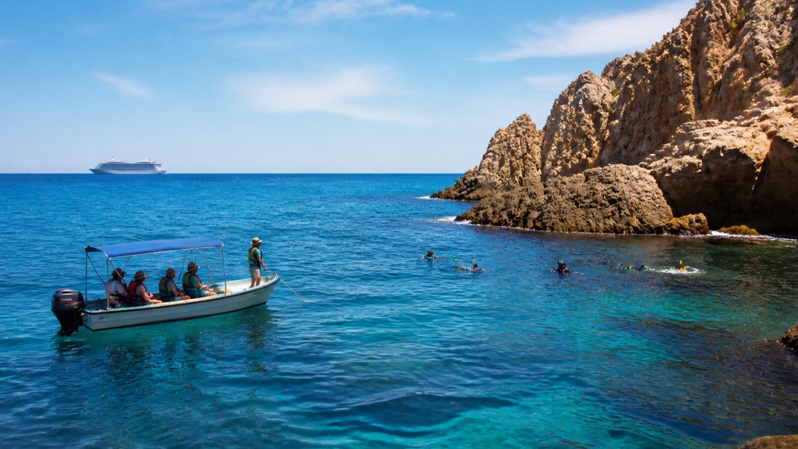 Small-boat excursion and snorkelers beside a rocky Mexican Pacific shoreline