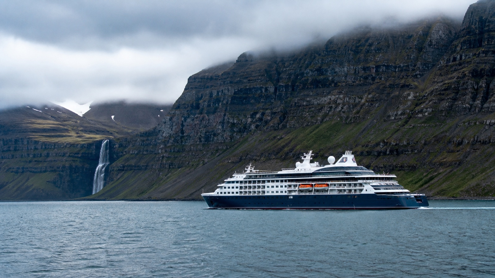 Unbranded cruise ship near Icelandic mountains under changeable northern light