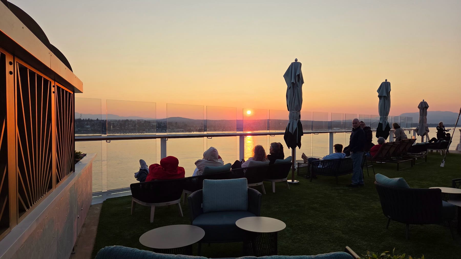 Passengers watching a warm sunset from an outdoor deck aboard Celebrity Solstice
