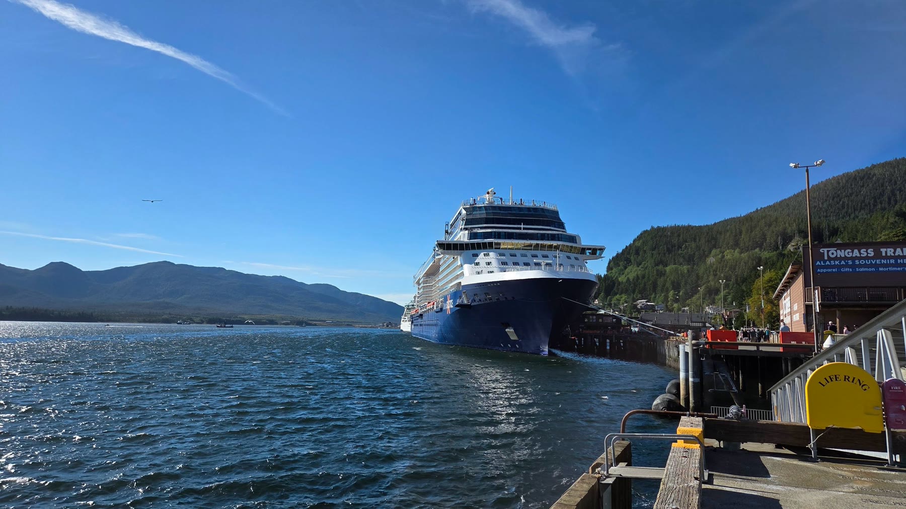 Celebrity Solstice docked beside the bright blue water and green mountains of Ketchikan