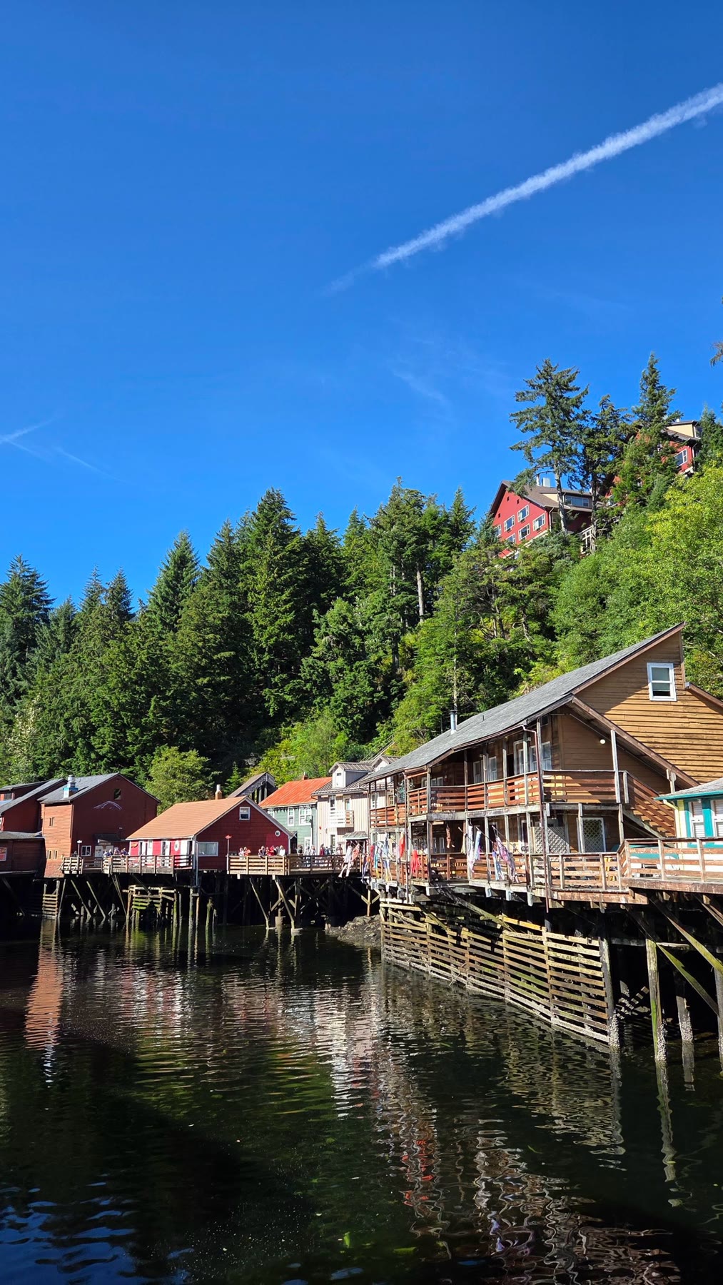 Historic Creek Street buildings on pilings above the water in bright sunshine